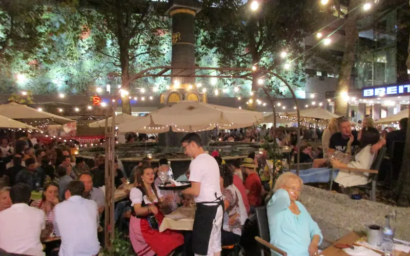 Stuttgart Wine Village in the evening - occupied tables under parasols and strings of lights